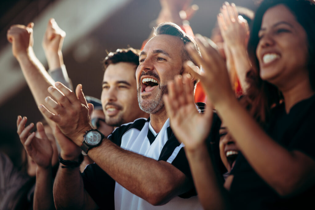 Group of soccer fans cheering to relate to sales tax at sporting events